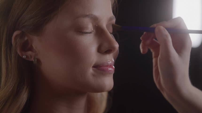 Makeup being applied to a womans eyelid with strong light in the background