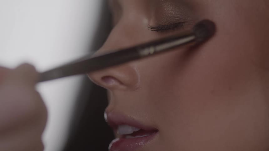 Close up of a young womans face while she is getting her makeup done in a studio