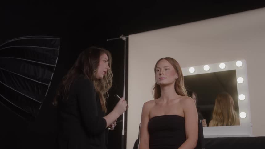 The makeup artist is applying makeup to the model in the studio
