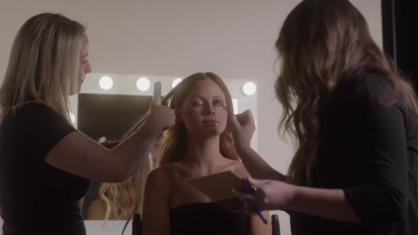 Stylists are working on the sitting model in the dressing room