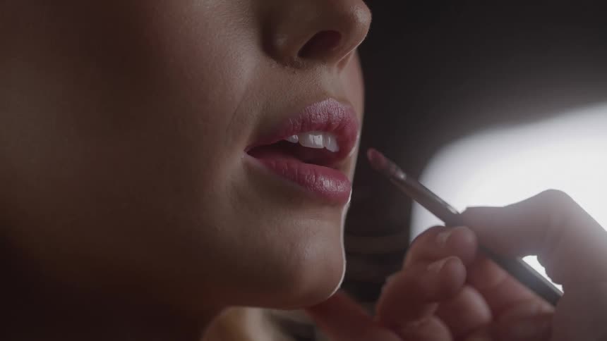 Makeup being applied to the lips of a woman indoors