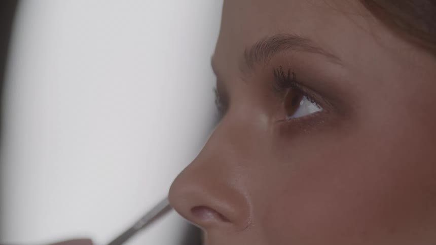 Makeup being applied to the eye area with a brush in a welllit setting