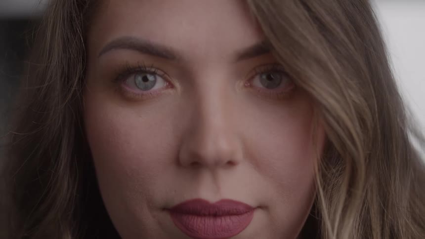 Womans face with light brown hair partially covering the eye and madeup lips