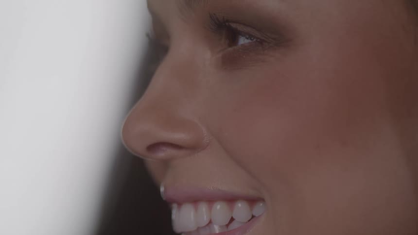 An extreme closeup side profile shot of a womans face shows her beginning with a closed mouth then opening the mouth with a makeup on her face