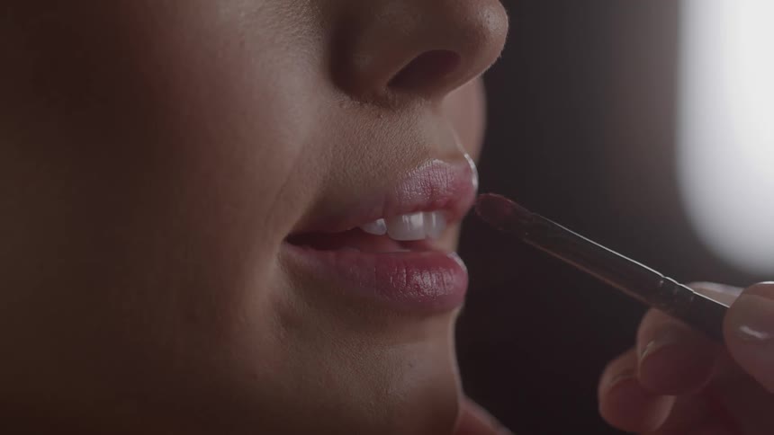 Closeup of a person having lip color applied with a makeup brush lips parted expression relaxed