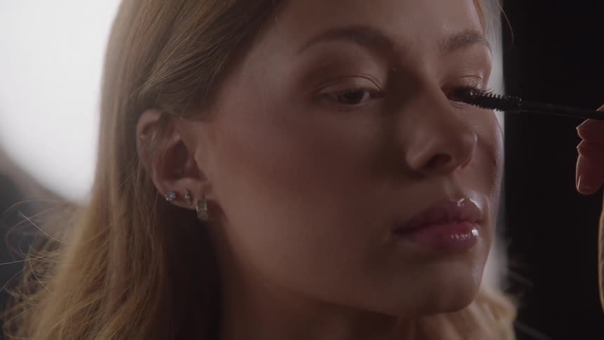 Close up of a young woman getting her face makeup done in a studio