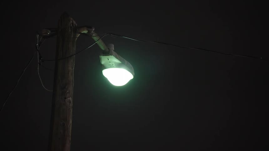 A malfunctioning streetlamp light flickering on and then burning out again