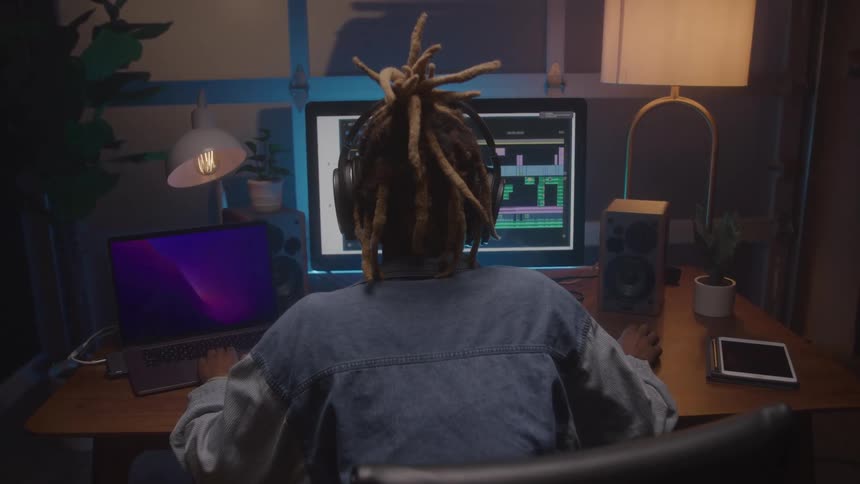 A person works on music production in a dim studio