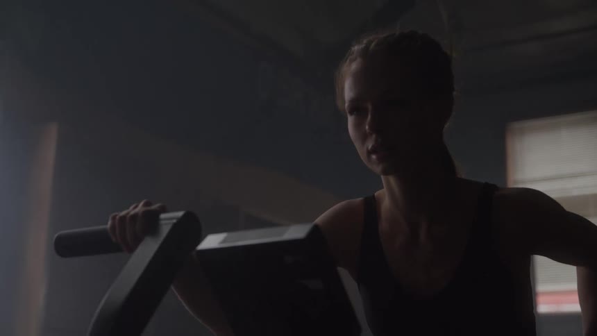 Woman exercises on a stationary bike indoors with soft light streaming through the window