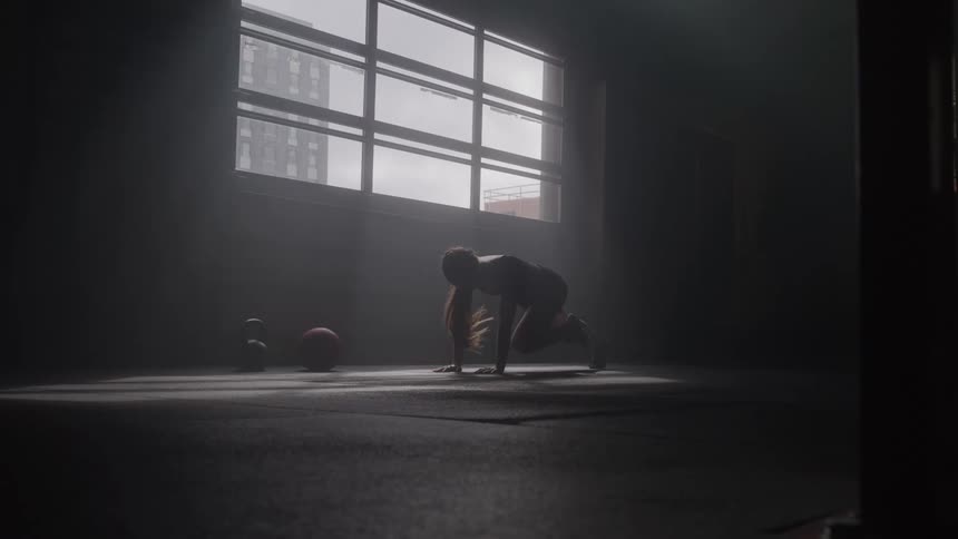 Woman training alone in a dim space with natural light streaming through the windows