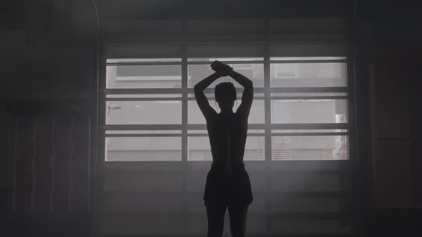 A young woman stretching while exercising in a room during daytime