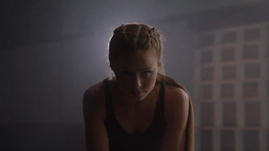 A young woman poses indoors with bright light shining behind her