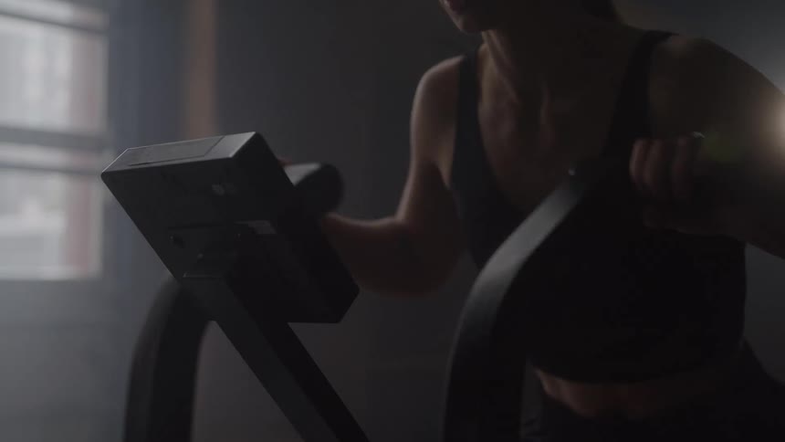 Woman works out intensely on a gym machine indoors