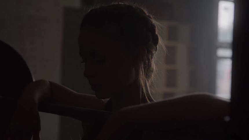 Silhouette of a woman resting with her arms on a bar in the dim light