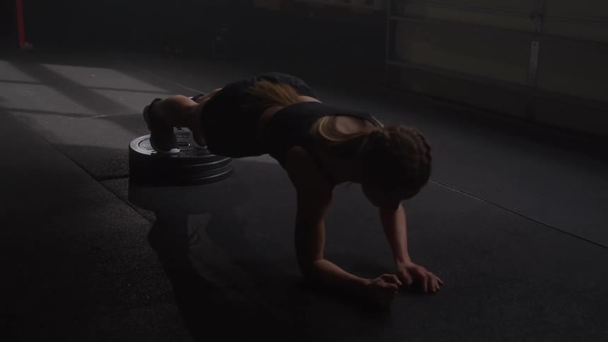 A woman does a plank while working out in the gym