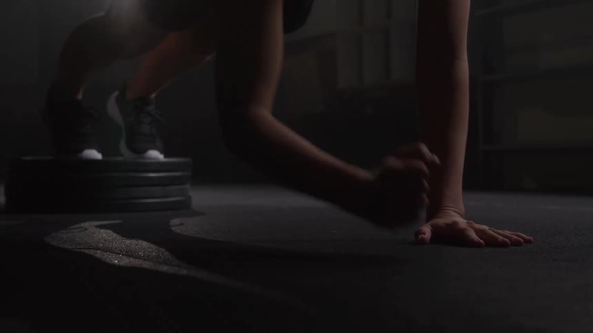 A young woman exercises in the gym holding a plank position