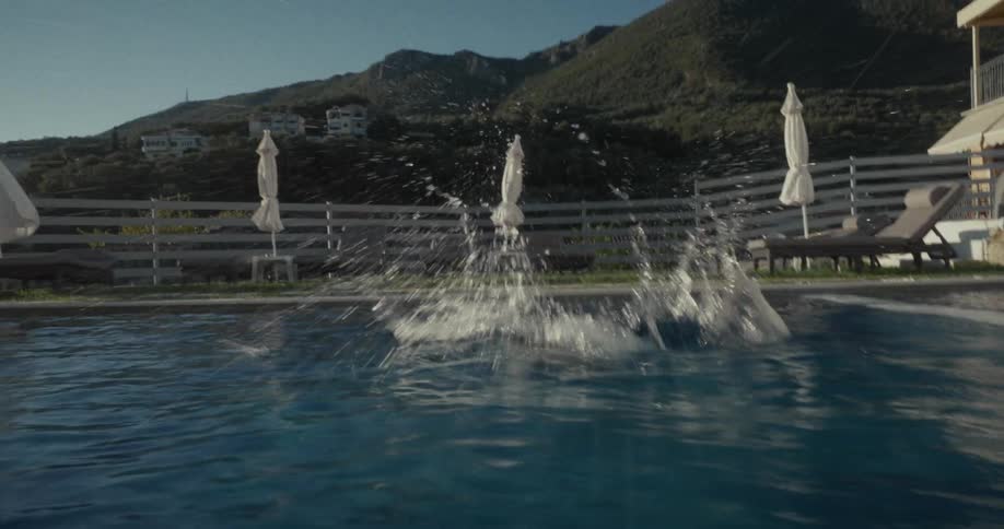 Boy in midair about to dive into a pool on a sunny day