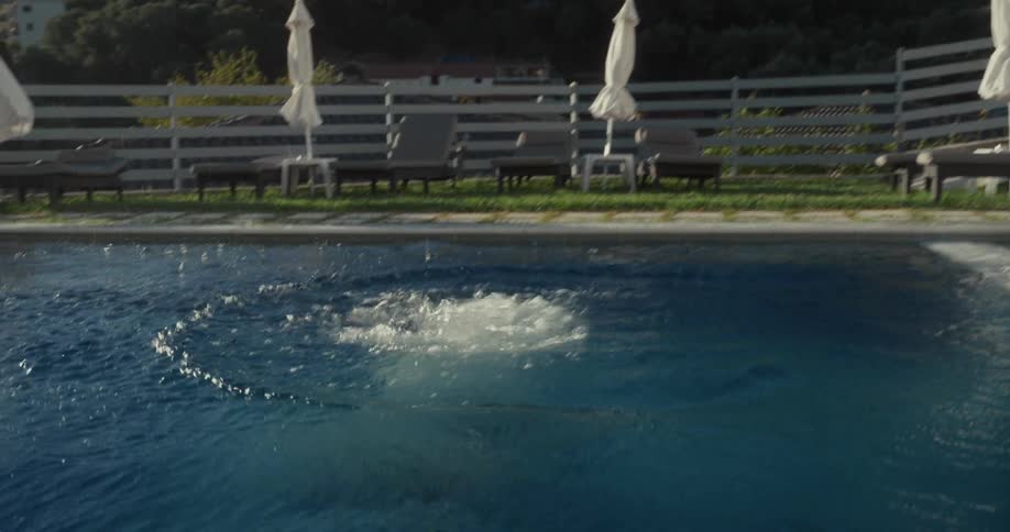 Boy cannondiving into the pool on a sunny day