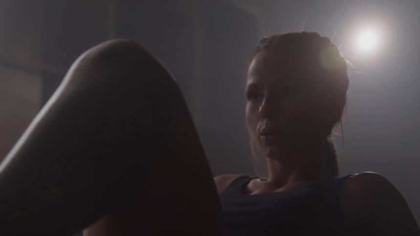 Woman performing an abdominal exercise in a dimly lit setting