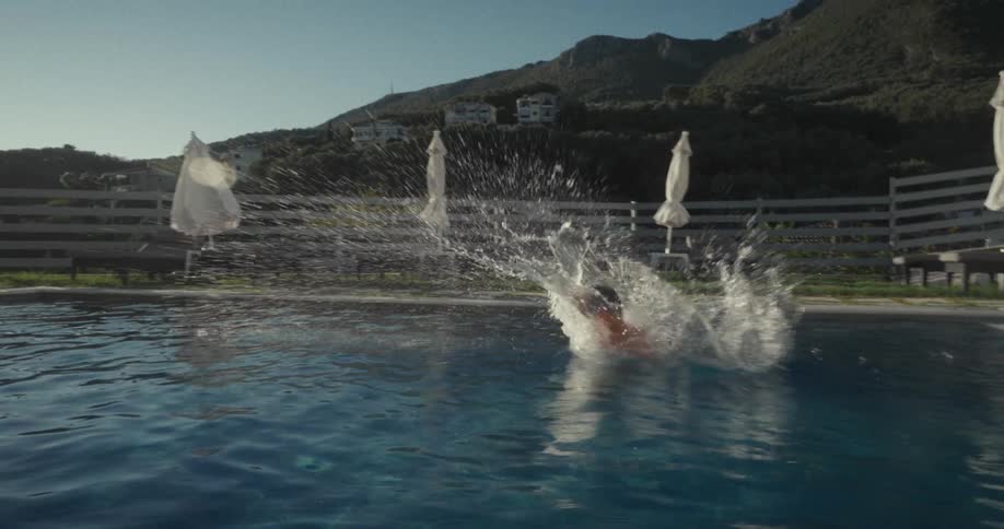 Boy running and jumping toward the pool on a sunny day