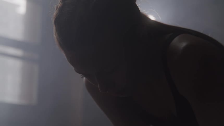 Person leaning forward in a dark setting with a tired expression