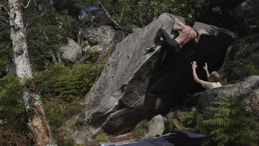 The man is rock climbing on the boulder