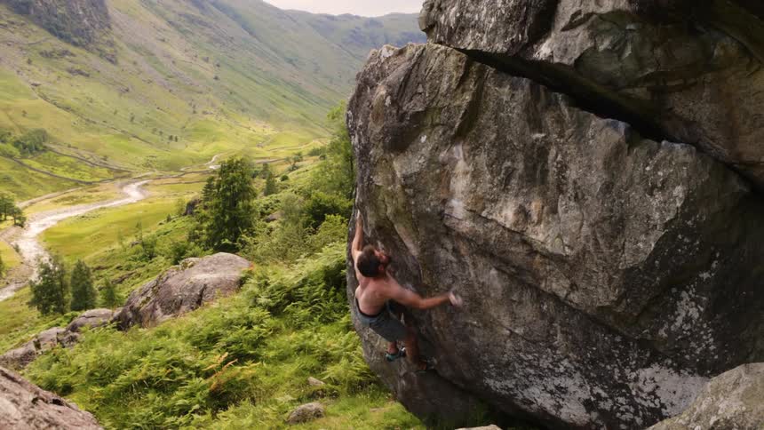 A man boulders on a large rock in the mountainous countryside