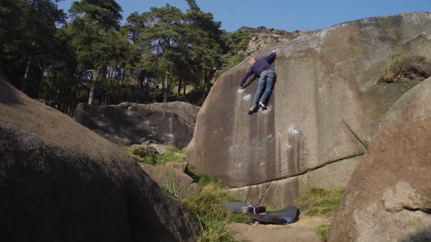 A man climbs a rocky terrain at midday