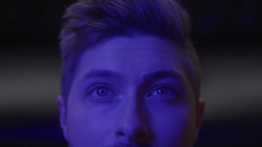 Face illuminated by light highlights light eyes looking upward