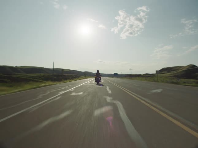 A person riding a motorcycle on a road in a rural area during daytime