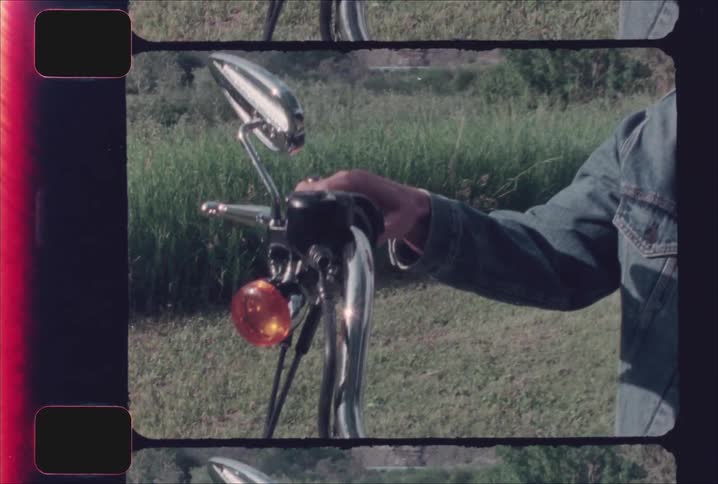 Hand grips the handlebar of a motorcycle in a green area