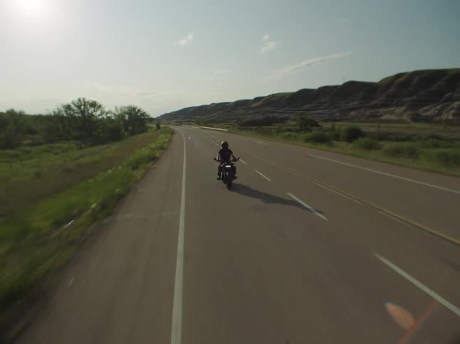 Motorcyclist rides along a road lined with guardrails among hills