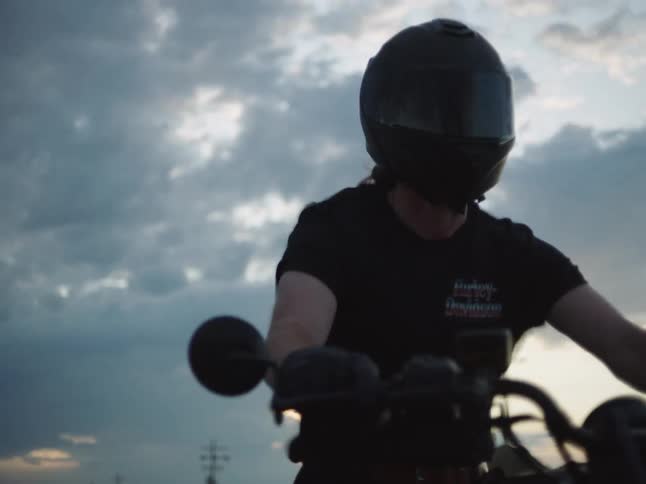 Male motorcyclist rides through the rural countryside after dusk during a road trip