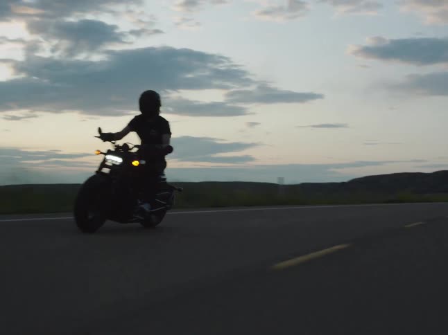 The man is riding on the long road on a cloudy day