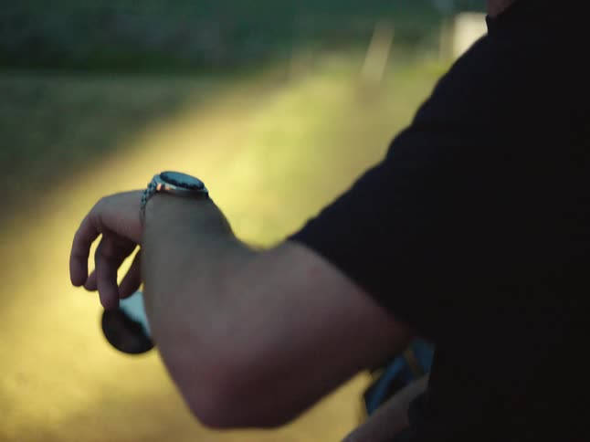 A man on a stopped motorcycle checks his wristwatch
