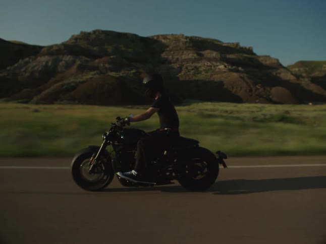 A man rides a motorcycle on a rural highway on a sunny day