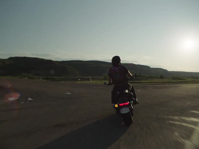 Motorcyclist rounds a curve on an open road at sunset