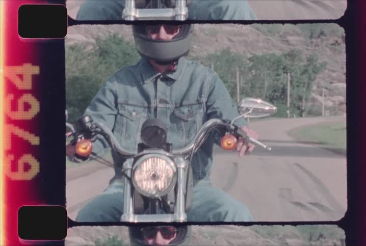 A man rides a motorcycle on a rural road on a sunny day