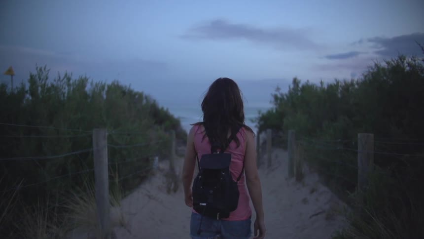 Woman walking down a small path on a cloudy day