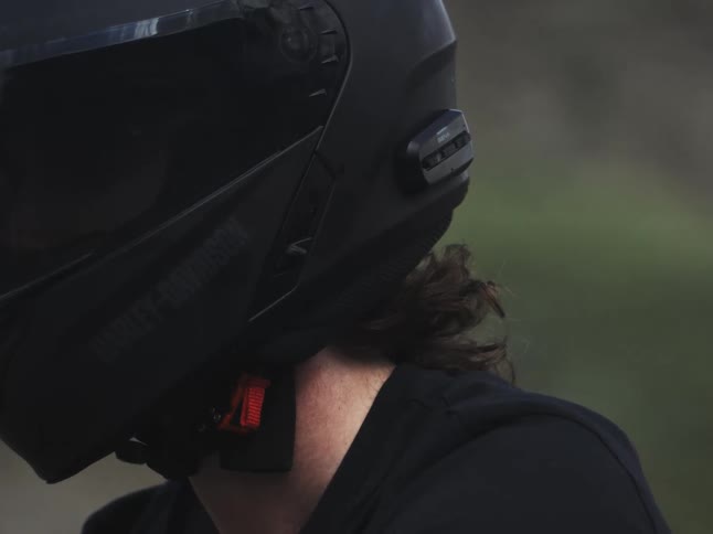 A motorcycle riders hair above their neck and under their helmet