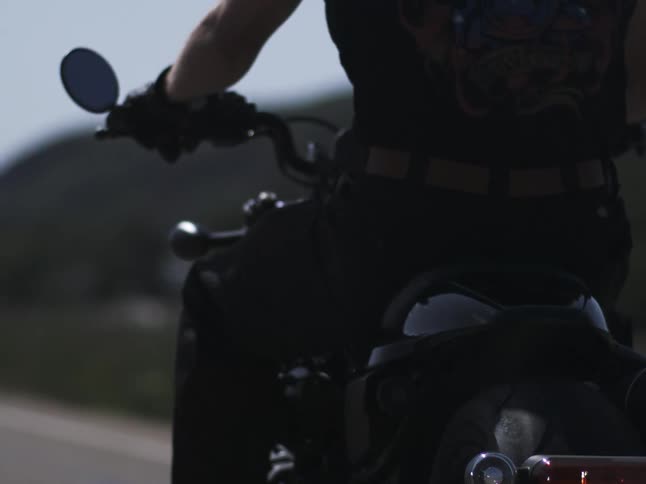 Motorcyclist rides the bike under strong light wearing a black tshirt