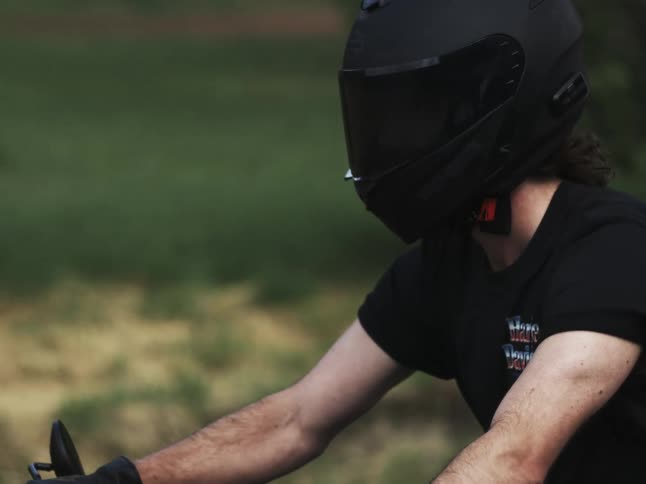 Motorcyclist wears a black fullface helmet while riding through nature