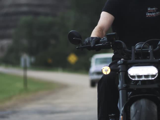 A person riding a motorcycle on a country road with an atv coming up behind them