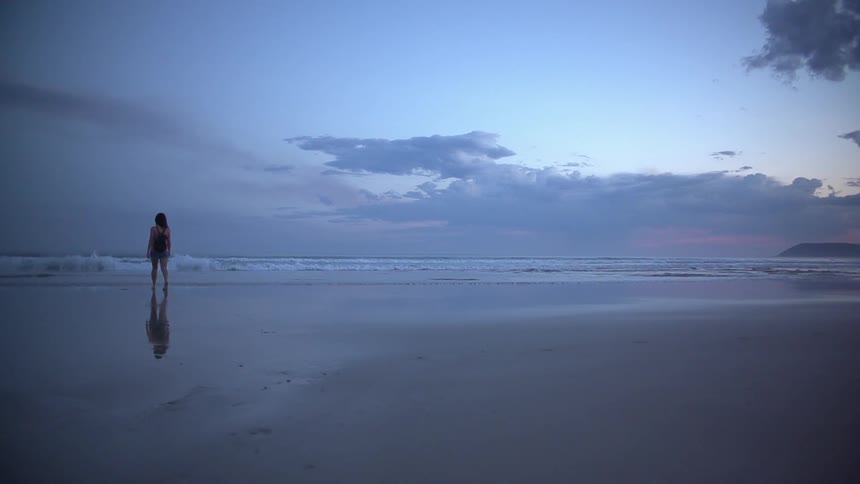Woman walking on a beach on a cloudy day