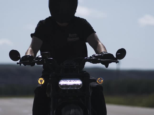 Motorcyclist travels along a rural highway on a windy day