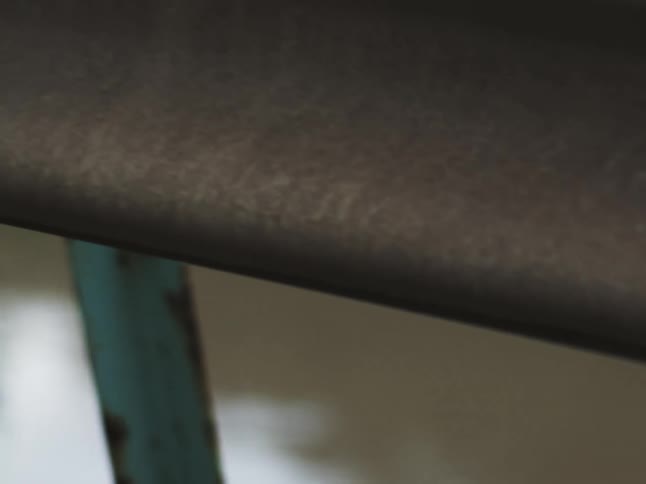 Detail of a rusty blue metal structure beneath a dark surface