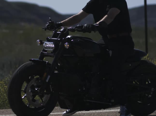 Motorcyclist puts his feet down while sitting on a stopped motorcycle during a road trip