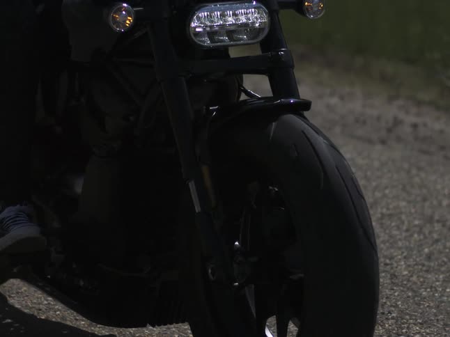 A motorcycles front tire as it rides over a gravel road