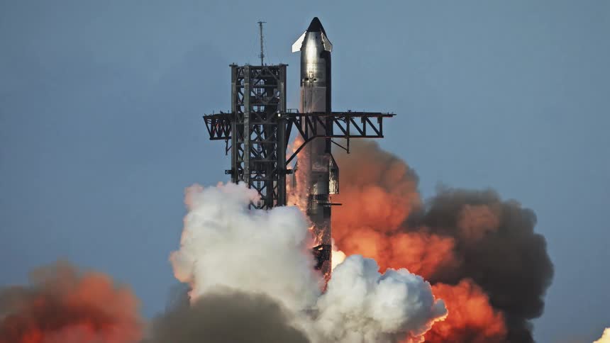 A massive rocket launches from its tower creating a huge plume of orange fire and black smoke that billows across the sky