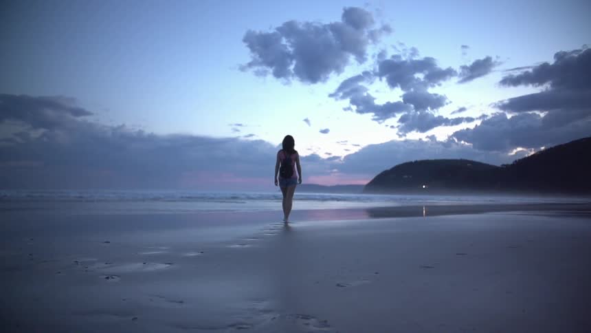 Woman walking on a beach at dusk